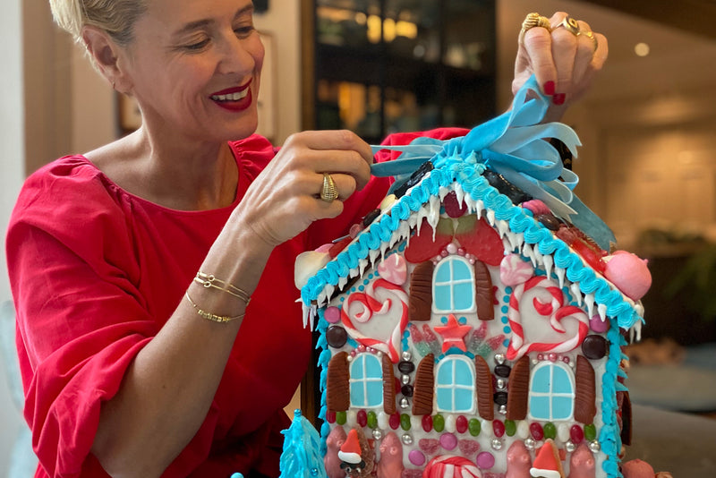 Deborah Brett finishes an elaborate gingerbread house with a blue bow.
