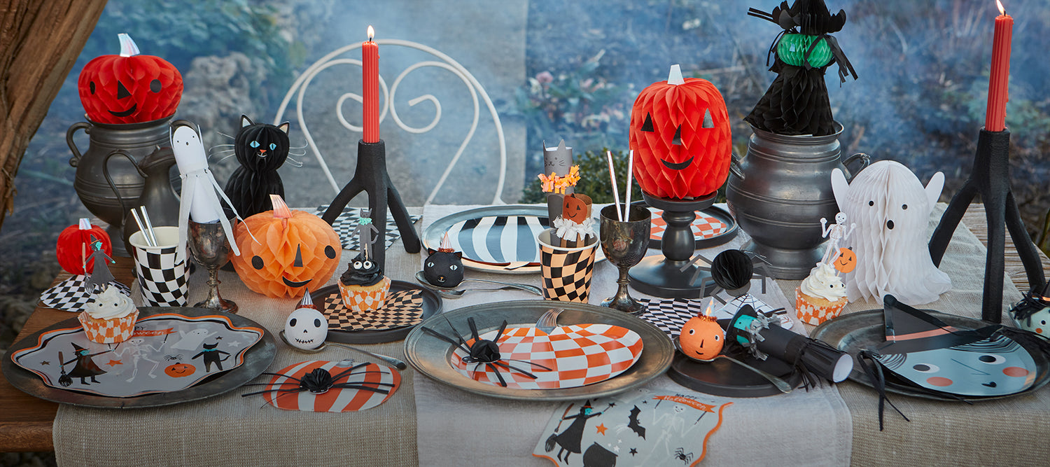 Lavish Halloween table with Meri Meri decorations including honeycomb pumpkins and Halloween-themed cups and plates