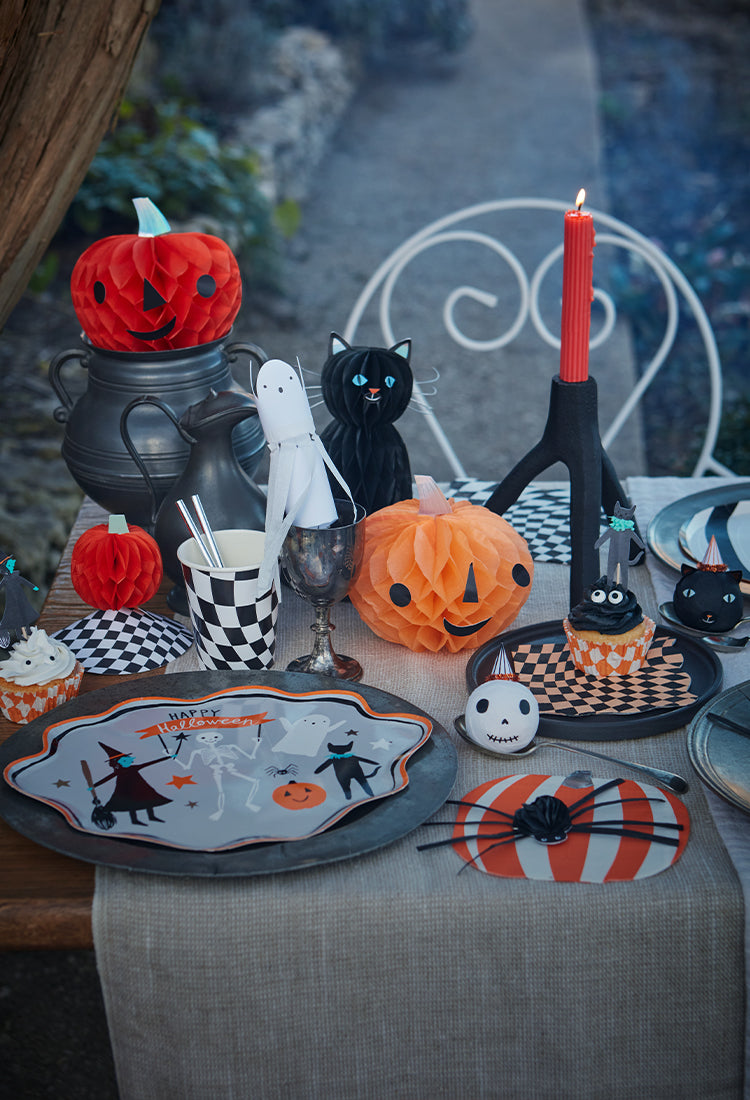 Lavish Halloween table with Meri Meri decorations including honeycomb pumpkins and Halloween-themed cups and plates