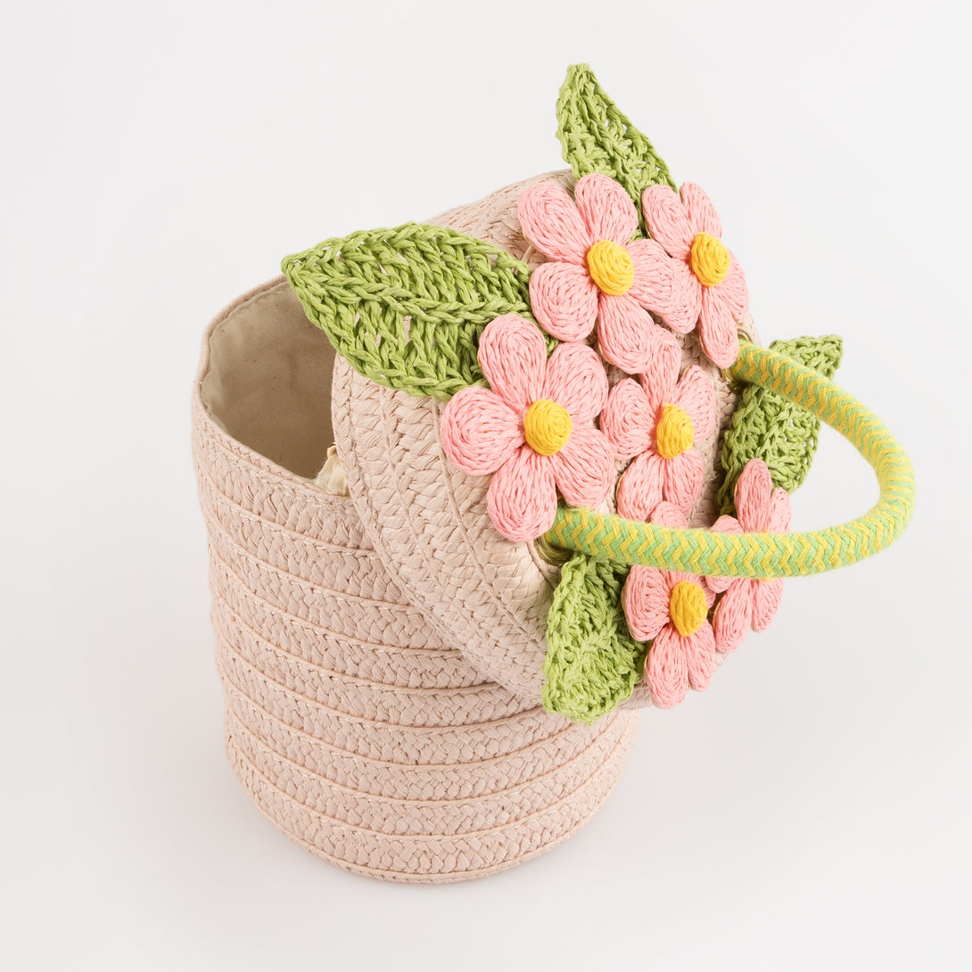 Our woven paper pink basket bag features paper flowers and leaves, a cord handle and a calico lining.