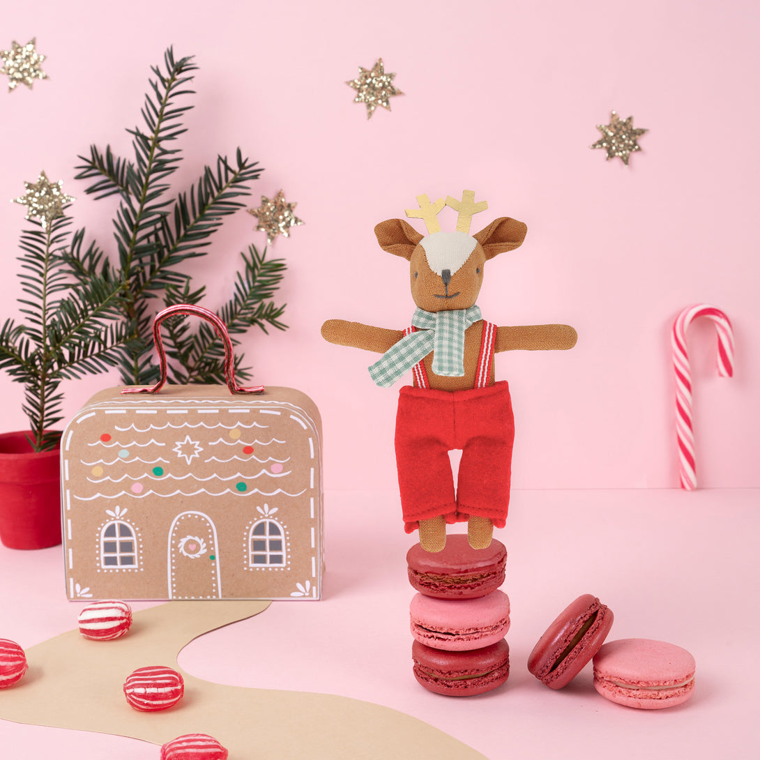 Our Christmas doll set includes a mini fabric reindeer doll in a laminated mini suitcase designed to look like a gingerbread house.