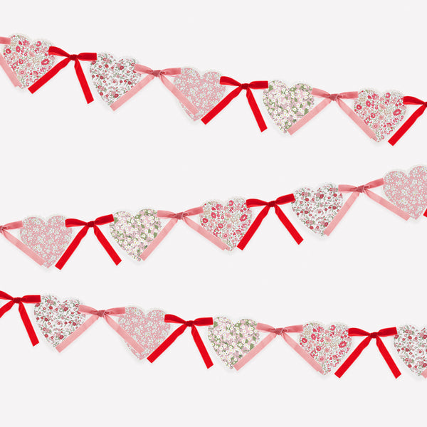 Our Valentine's Day garland feature paper hearts with floral Liberty print designs and pink and red luxe velvet bows. Image1