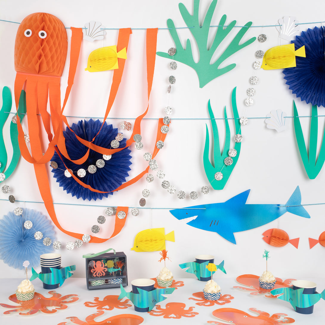 Our special under the sea set includes a stunning sea garland, plates, napkins, cupcake kit and 3D shark cups. 