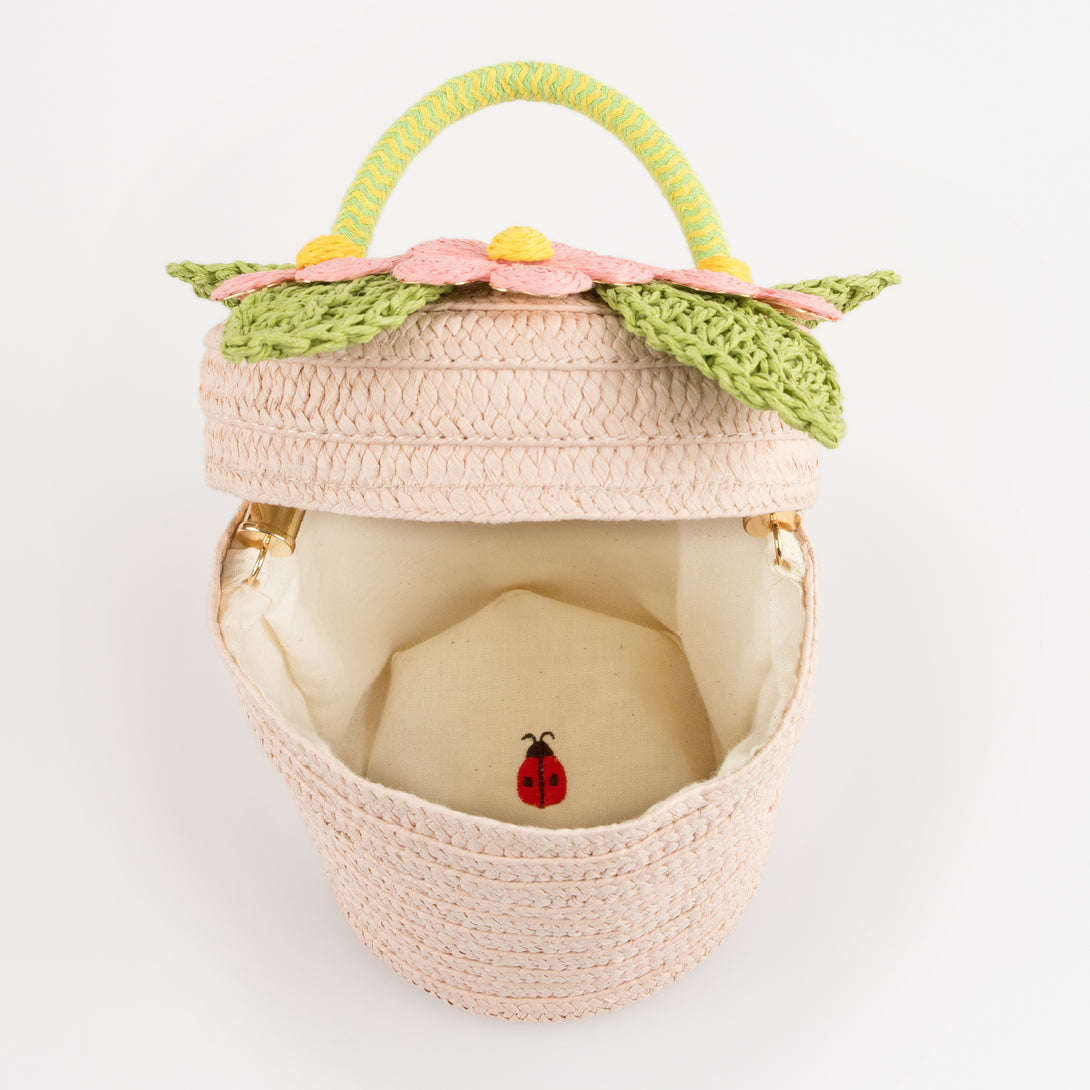 Our woven paper pink basket bag features paper flowers and leaves, a cord handle and a calico lining.