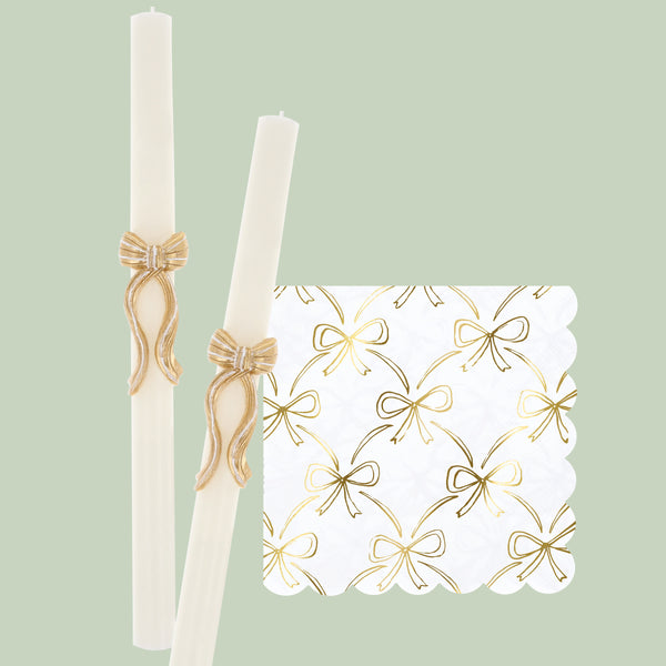 Our golden Christmas host gift set includes two table candles, with gold stripy bow details, and a pack of paper napkins with gold bow designs. 