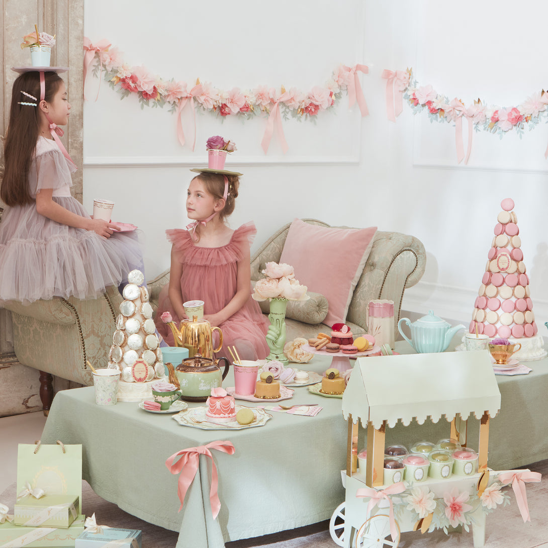 Beautiful pastel plates, cups, napkins, floral garland, and a centrepiece to display macarons. 