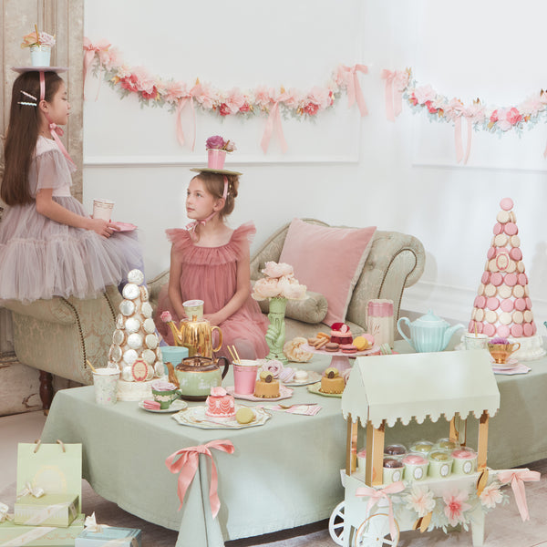 Beautiful pastel plates, cups, napkins, floral garland, and a centrepiece to display macarons. 