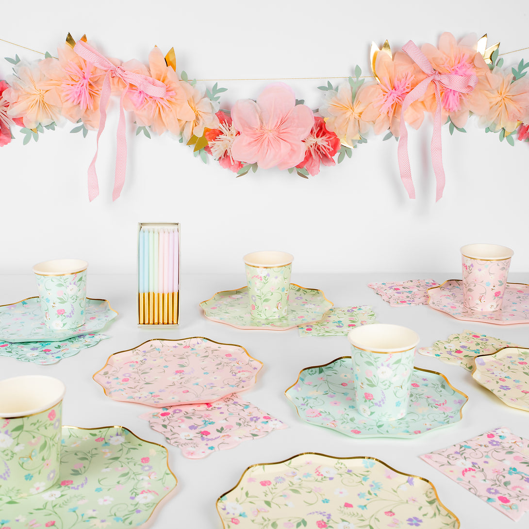 Beautiful pastel floral plates, cups, napkins, floral garland, and gold candles. 