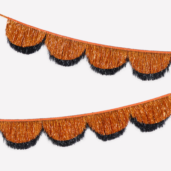 Our Halloween garland features 2 foil tinsel fringe layers in classic orange and black, with scalloped shapes, that catch the light beautifully. Image1