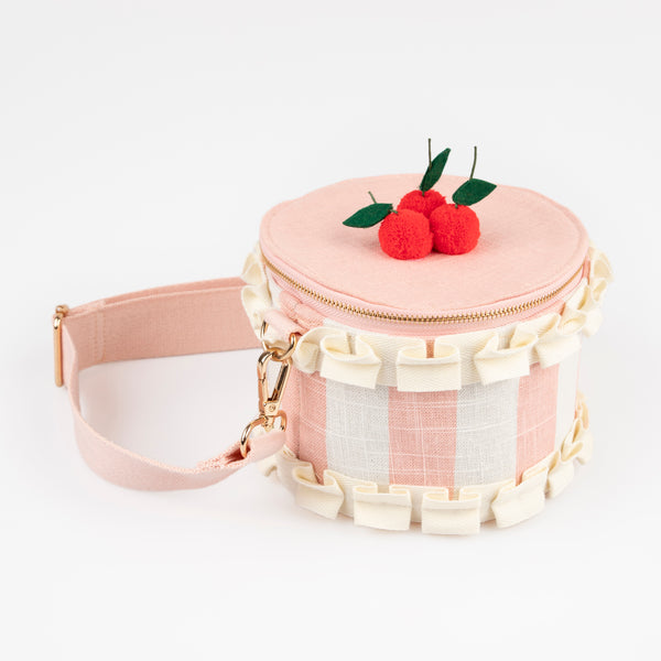 Our pink fabric bag, crafted to look like a cake, features fun pompom cherries, felt leaves, a ruffled ribbon and a long webbing handle.