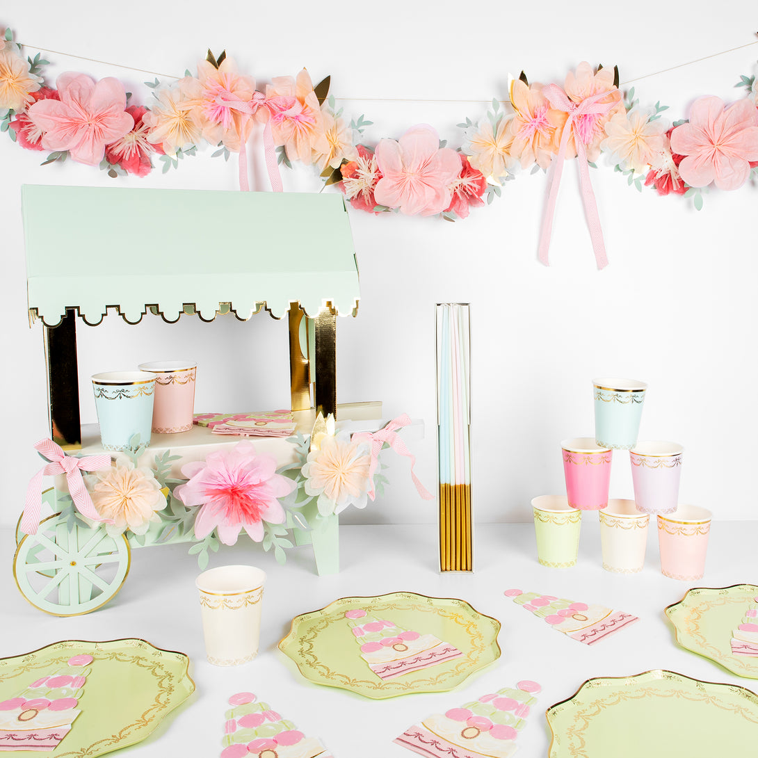 Beautiful pastel plates, cups, napkins, floral garland, and a centrepiece to display macarons. 