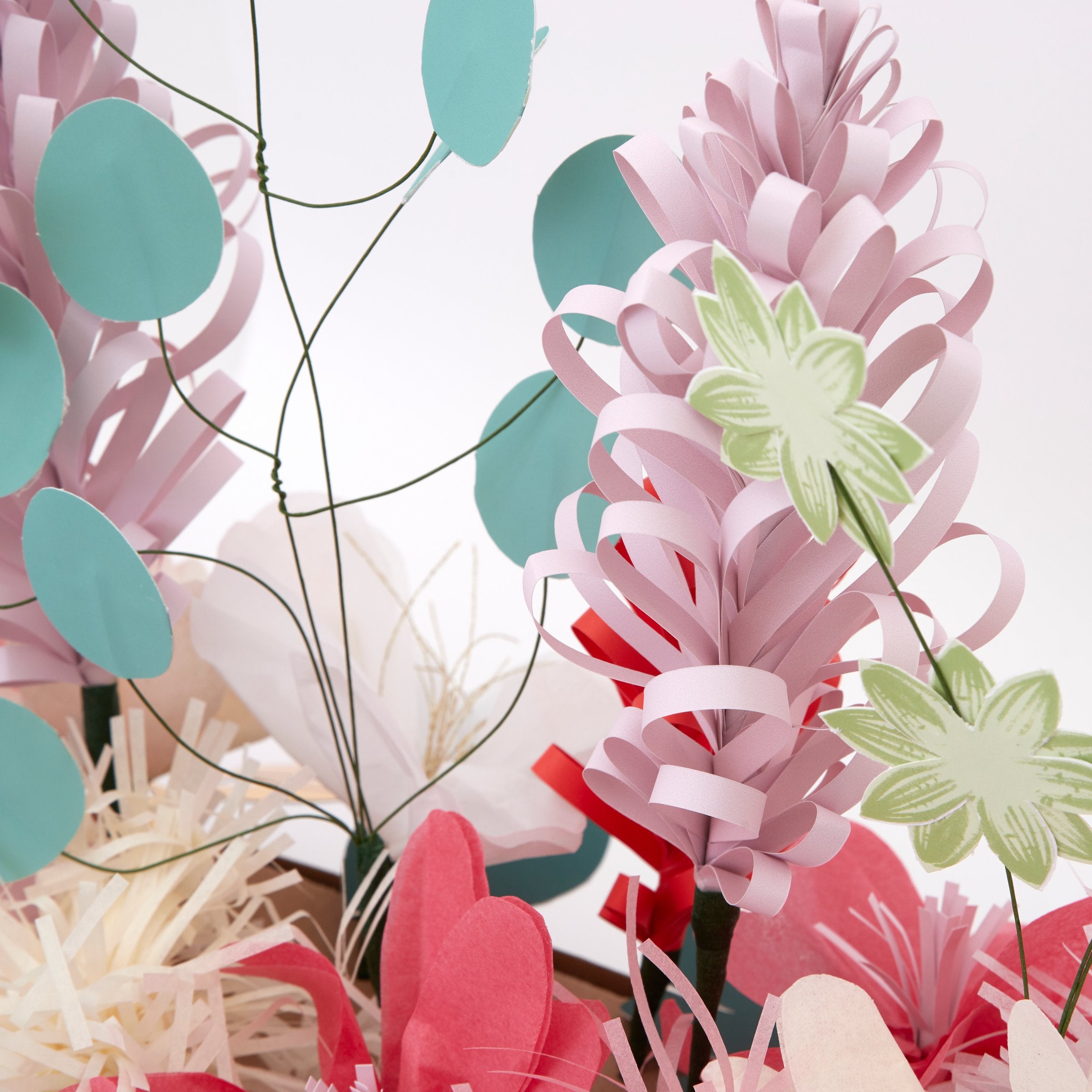 This Christmas table decoration is crafted from tissue paper flowers and foil topped paper leaves for a special look.