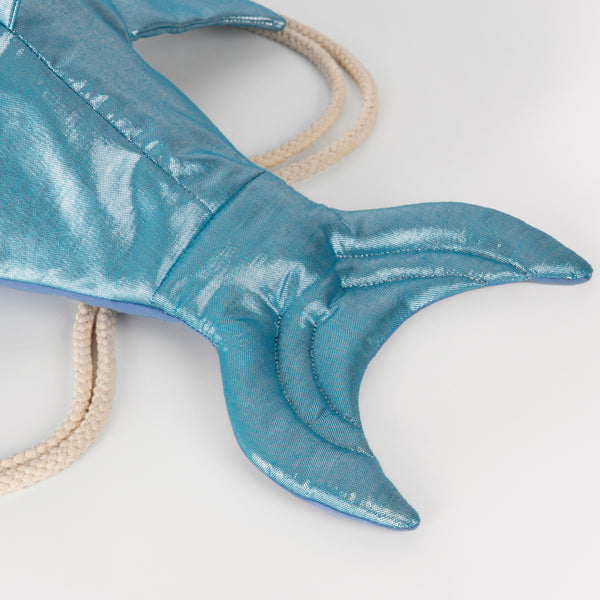 This shiny shark is  a backpack crafted from blue lamé fabric with a cotton lining and cord straps. Image3