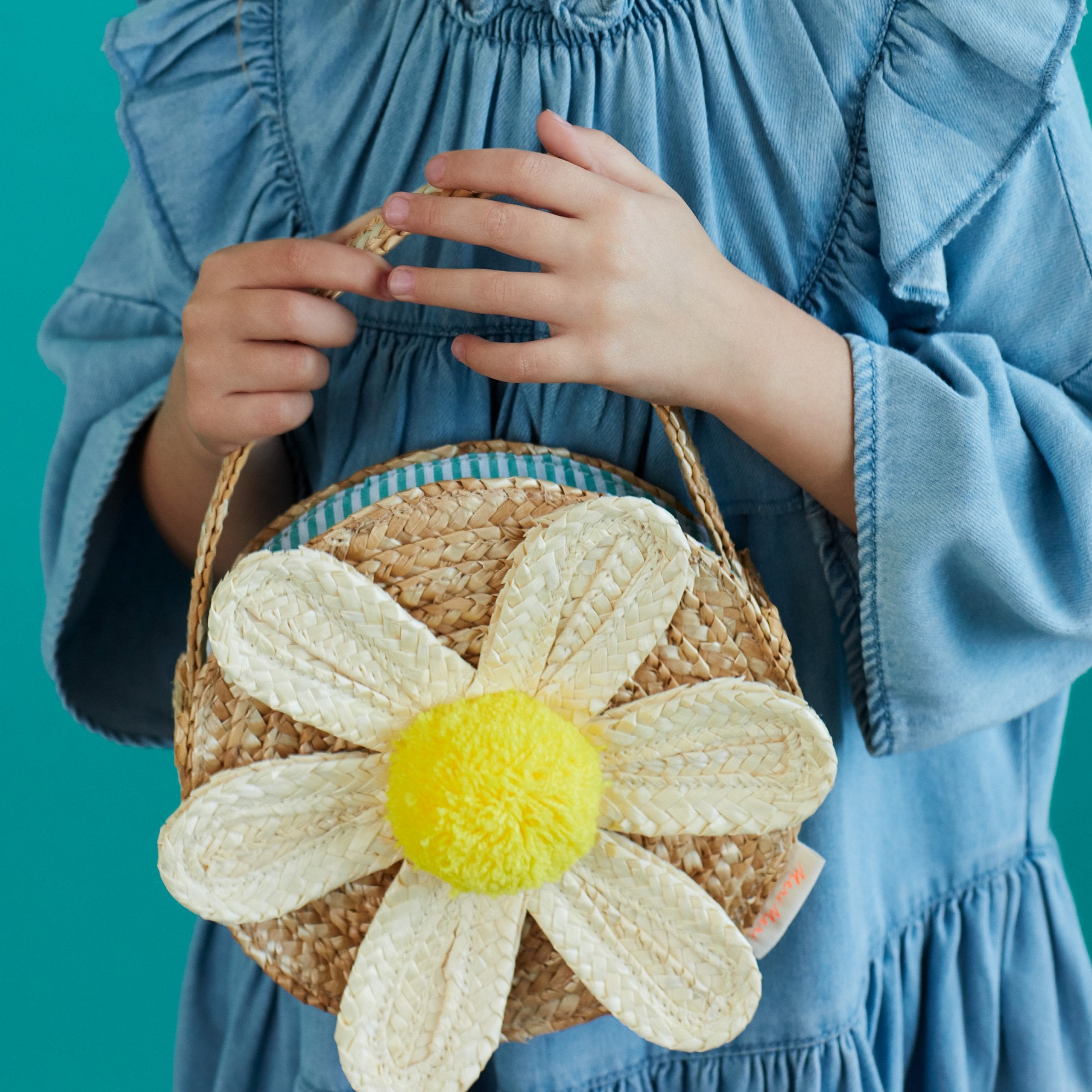 This sensational straw kids bag has a raffia daisy with a yellow pompom in the centre.